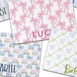 May include: Personalised pet feeding mat with two white bowls and a blue floral design. The mat has the name "Lucy" printed on it.