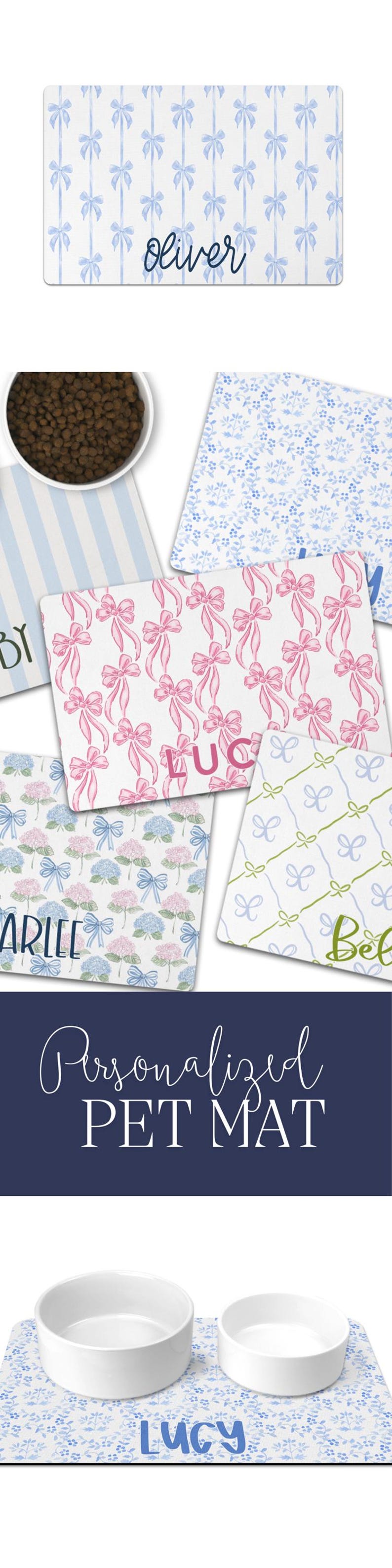 May include: Personalised pet feeding mat with two white bowls and a blue floral design. The mat has the name "Lucy" printed on it.