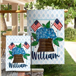 May include: A garden flag featuring a blue floral arrangement with two American flags and the name "William" in a script font. The background has a light blue pattern.