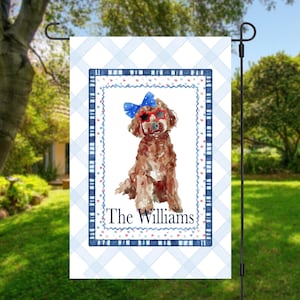 May include: A rectangular garden flag featuring a light blue and white gingham background. The center displays a watercolor illustration of a brown dog wearing a blue bow and red star-shaped sunglasses, with the text The Williams below it.