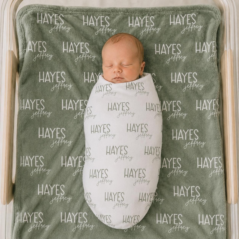 K&ouml;nnte beinhalten: Eine salbeigr&uuml;ne Babydecke mit einem sich wiederholenden Muster des Namens Hayes Jeffrey in wei&szlig;em Text, mit einem gepuckten S&auml;ugling in der Mitte. Der S&auml;ugling ist in eine wei&szlig;e Puckdecke gewickelt, die ebenfalls mit dem Namen Hayes Jeffrey bedruckt ist.