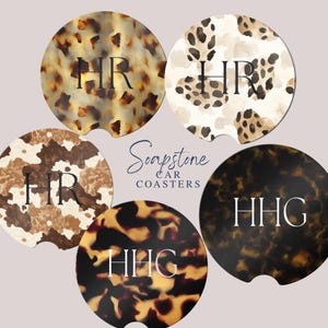 May include: Five car coasters with animal print designs, including leopard and cow patterns, and a tortoiseshell pattern. Each coaster features a monogram in a serif font. The text "Soapstone Car Coasters" is also present.
