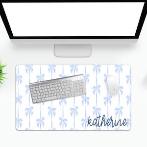 May include: A white desk mat with a light blue watercolor bow pattern. The mat has the name "katherine" written in dark blue cursive at the bottom.