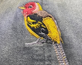 May include: A gray baseball cap with an embroidered yellow, black, and red bird design.