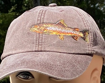 May include: A brown baseball cap with an embroidered image of a trout fish.