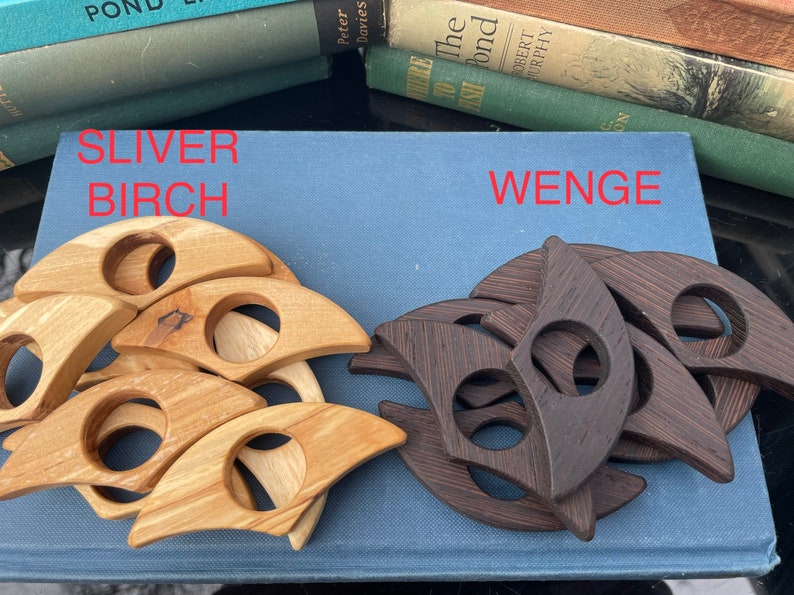 Op de afbeelding: Twee sets houten ringhouders, &eacute;&eacute;n set is lichtbruin en gelabeld "SLIVER BIRCH" en de andere set is donkerbruin en gelabeld "WENGE".
