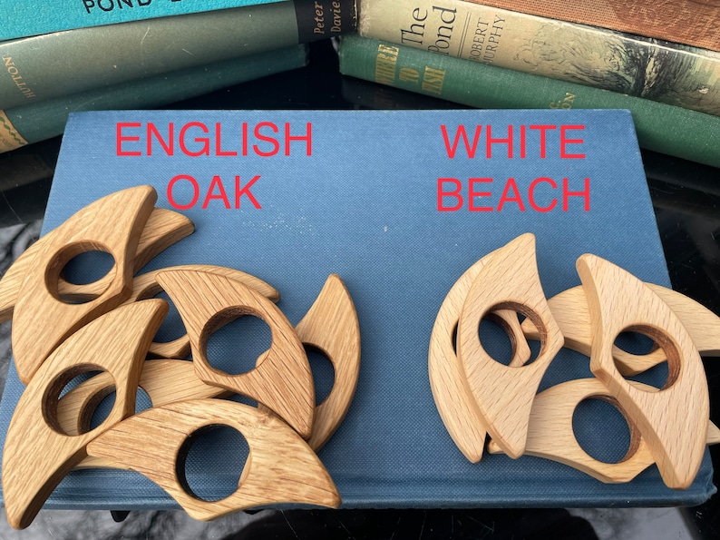 Op de afbeelding: Twee sets houten ringhouders, &eacute;&eacute;n set is gemaakt van Engelse eik en de andere van wit strandhout. Beide sets zijn in een cirkelvormige opstelling.