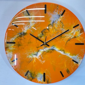 Puede incluir: Reloj de resina abstracta naranja, negro y blanco con manecillas negras. La esfera del reloj tiene un diseño de mármol y remolino.