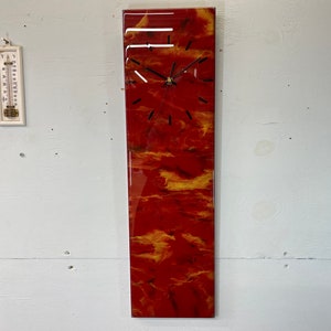 May include: A rectangular wall clock with a red and gold marbled design. The clock has black hands and hour markers. The clock is approximately 48 inches tall.