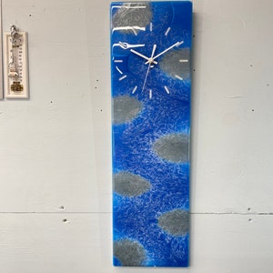 May include: A blue and gray resin clock with white hands. The clock face is surrounded by a blue resin background with gray swirls.