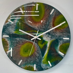 May include: A round clock with a green, brown, and white abstract design. The clock face has white hour markers and white hands.