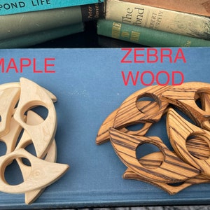 Op de afbeelding: Twee sets houten boekenleggers, een set gemaakt van esdoornhout en de andere van zebrahout. Beide sets hebben de vorm van een halve maan.