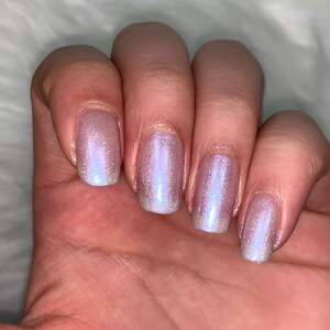 May include: Five fingernails painted with a light purple iridescent nail polish.