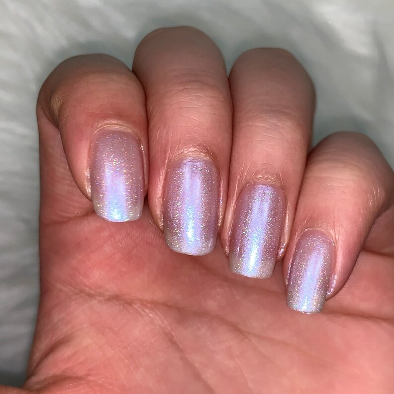May include: Five fingernails painted with a light purple iridescent nail polish.