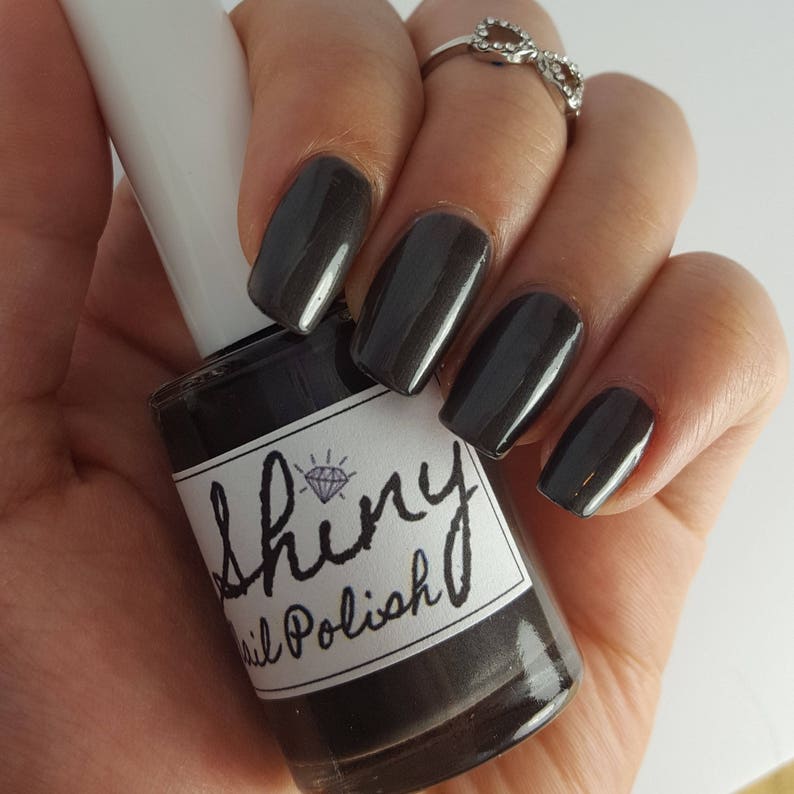 May include: A bottle of dark gray nail polish with a diamond logo and the text "Shiny Nail Polish".