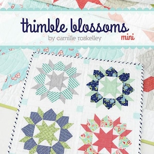 May include: A white quilt with four starburst designs in shades of blue, green, and red. The quilt features the text "thimble blossoms" and "swoon #170". The quilt is a mini version.