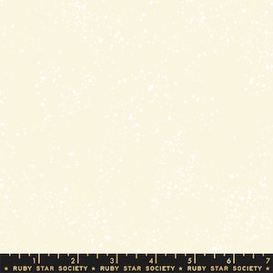 May include: A cream-colored fabric with a white speckled pattern. The fabric has a subtle texture and a slightly off-white background.