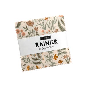 May include: A fabric square with a floral print in shades of pink, green, and brown. The fabric is labeled "RAINIER by Jessica  Roop" with a Moda Fabrics logo.