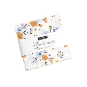 May include: A stack of fabric squares with a floral pattern in shades of blue, yellow, and white. The fabric is wrapped with a white band that reads "Sun-drenched" by Sweetfire Road Designs.