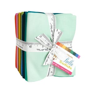May include: A stack of colorful fabric squares, wrapped with a white measuring tape ribbon. The fabric bundle includes shades of green, pink, yellow, and blue. A tag reads "Bella Solids" and "Fabrics-Supplies".