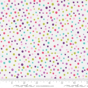 May include: White fabric with a scattered pattern of colorful polka dots in shades of pink, purple, green, and teal. The fabric has a ruler printed along the bottom edge, with the word "moda" printed in a stylized font.