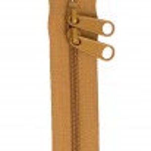 May include: A tan zipper with two metal sliders and a closed end. The zipper is approximately 12 inches long.