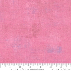 May include: A solid pink fabric with a subtle textured pattern. The fabric has a slightly faded look, with hints of light purple throughout. The fabric is measured in inches with a ruler at the bottom of the image.