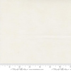 May include: Cream-colored fabric with a subtle woven texture. A ruler is printed along the bottom edge, marked with inch increments. The fabric appears to be cotton or a similar material, suitable for quilting or sewing projects.