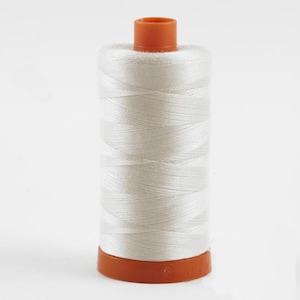 May include: A spool of white thread with an orange plastic bobbin.