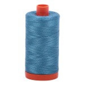 May include: A spool of teal blue thread with a red plastic bobbin.