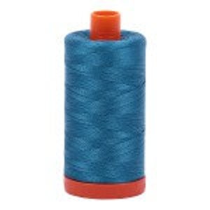 May include: A spool of teal blue thread with an orange plastic bobbin.