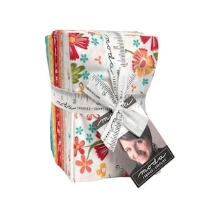 May include: A stack of colorful fabric squares tied with a white ribbon printed with a ruler design. The fabric features floral patterns in red, orange, and turquoise on a white background. A tag with a woman's photo and the words "moda FABRICS + SUPPLIES" is attached.