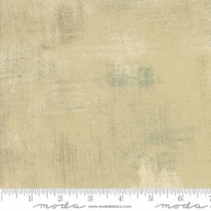 May include: A beige fabric with a subtle, textured pattern of light green and gray brushstrokes. The fabric has a soft, slightly distressed look.