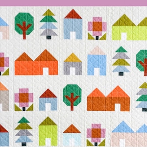 May include: A colorful quilt with a pattern of houses, trees, and flowers. The quilt is made up of squares of different colors and patterns. The quilt is called "Tiny Town Quilt".