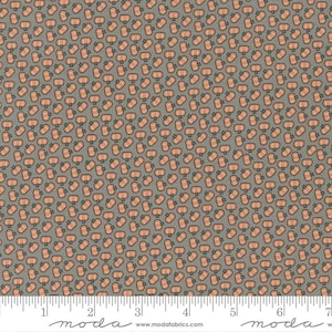 May include: A gray fabric with a repeating pattern of small orange pumpkins. The fabric has a ruler with the words "moda" and "www.modafabrics.com" printed on it.