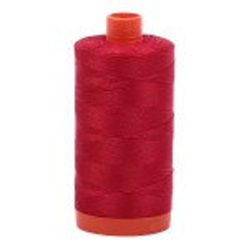 May include: A spool of red sewing thread with an orange plastic bobbin.