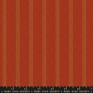 May include: Close-up of a textured fabric with vertical stripes. The fabric is a warm, reddish-orange color with thin, golden-yellow stripes running down the length. The bottom of the image has a ruler with the text "RUBY STAR SOCIETY".