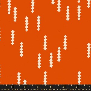 May include: Orange fabric with a repeating pattern of off-white, zig-zag shapes. The fabric has a speckled texture and a ruler along the bottom edge with the text "RUBY STAR SOCIETY".