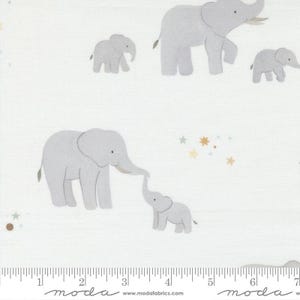 May include: White fabric featuring a repeating pattern of gray elephants in various sizes. Some elephants are interacting, with stars and dots scattered throughout the design. The fabric has a ruler along the bottom edge.