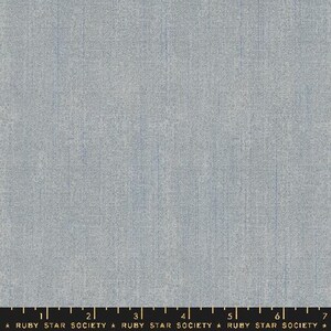 May include: A close-up of a light blue fabric with a subtle textured pattern. The fabric has a slightly grainy appearance, giving it a rustic feel.