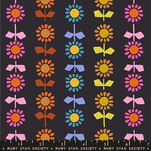 May include: Dark gray fabric with a repeating pattern of stylized flowers and bows in shades of orange, pink, yellow, and blue. The flowers have a central circle and petal design. The bows are positioned between the flowers. The text "RUBY STAR SOCIETY" is at the bottom.