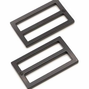 May include: Two black metal slider buckles. The buckles are rectangular with two parallel slots in the center.