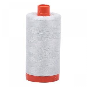 May include: A spool of white thread with an orange top and base. The thread is tightly wound around the spool, creating a cylindrical shape. The thread appears to be a light, neutral color, suitable for various sewing projects.
