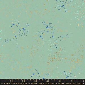 May include: A light blue fabric with a speckled pattern of gold and blue dots. The fabric is marked with a ruler and the text "RUBY STAR SOCIETY".