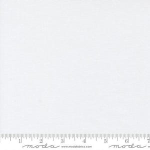 May include: A plain white fabric with a subtle texture. The fabric is shown with a ruler for scale.