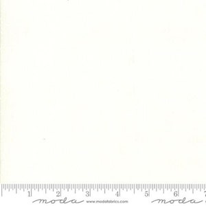 May include: A plain white fabric with a subtle texture. The fabric is shown with a ruler for scale.