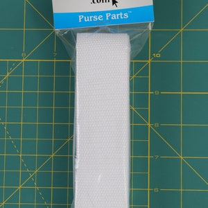 May include: White cotton webbing strap, 1 inch wide, packaged in a clear plastic bag with a blue and white label that reads "by annie.com Purse Parts".
