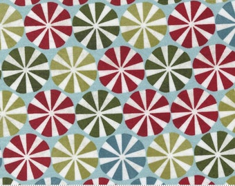 Könnte beinhalten: Ein blauer Stoff mit einem sich wiederholenden Muster aus weißen, roten und grünen Windrädern. Der Stoff ist mit einem Zollstock und den Worten "moda" und "www.modafabrics.com" gekennzeichnet.