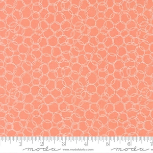 May include: Coral fabric with a repeating pattern of overlapping white circles. The fabric has a textured appearance and is suitable for quilting or other craft projects. The image includes a ruler along the bottom edge for scale.