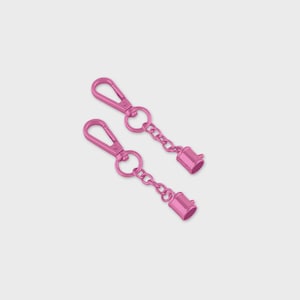 May include: Two pink metal keychains with lobster claw clasps, round rings, and short chains. Each chain ends with a small, cylindrical charm. The keychains are a bright, solid pink color.
